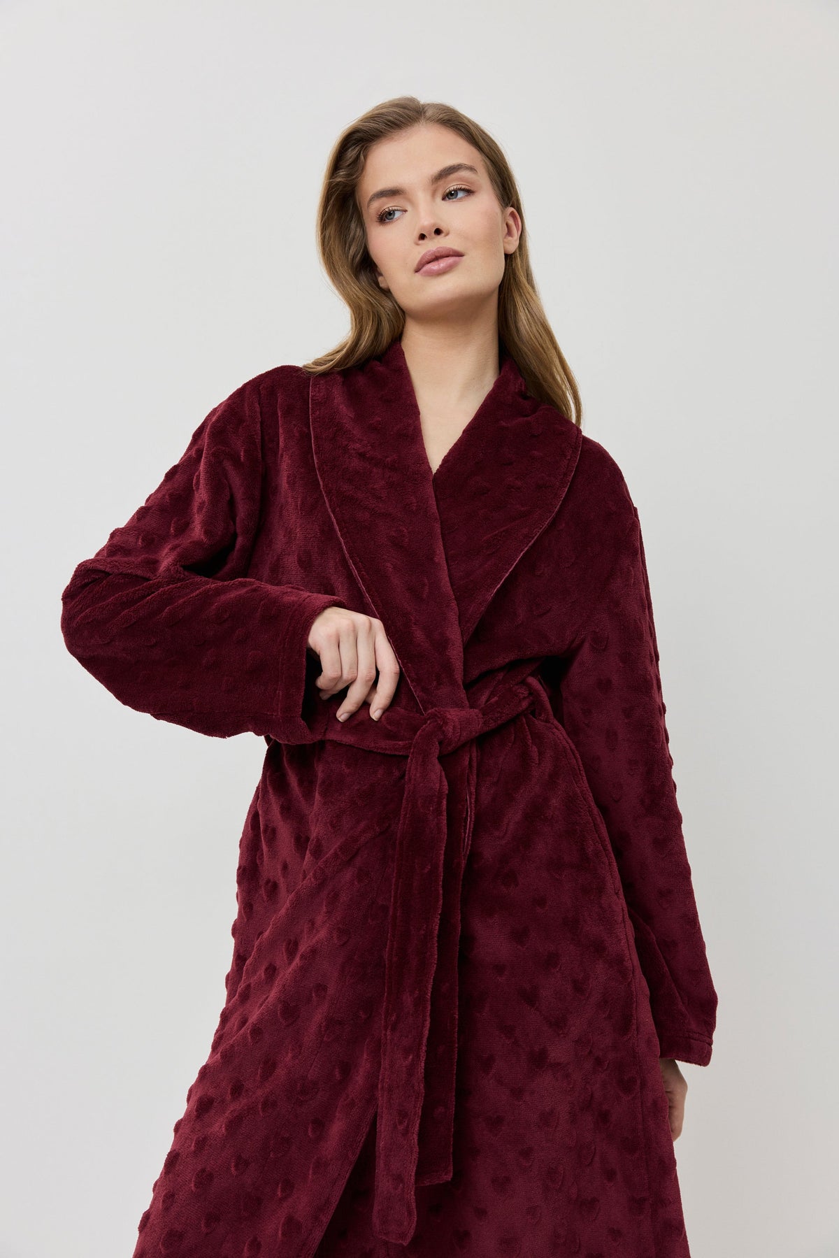 Woman wearing a burgundy robe against a white background