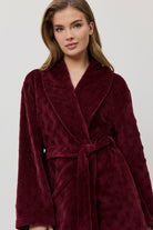 Woman wearing a burgundy robe against a white background