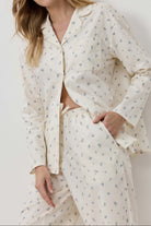 Woman wearing a cream-colored pajama set with floral pattern against a white background