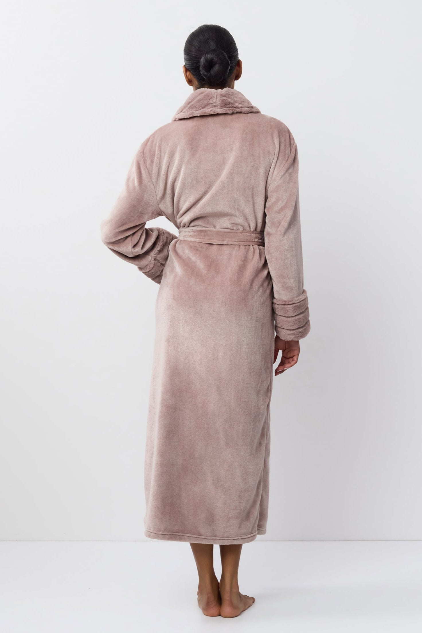 Person wearing a plush bathrobe against a white background