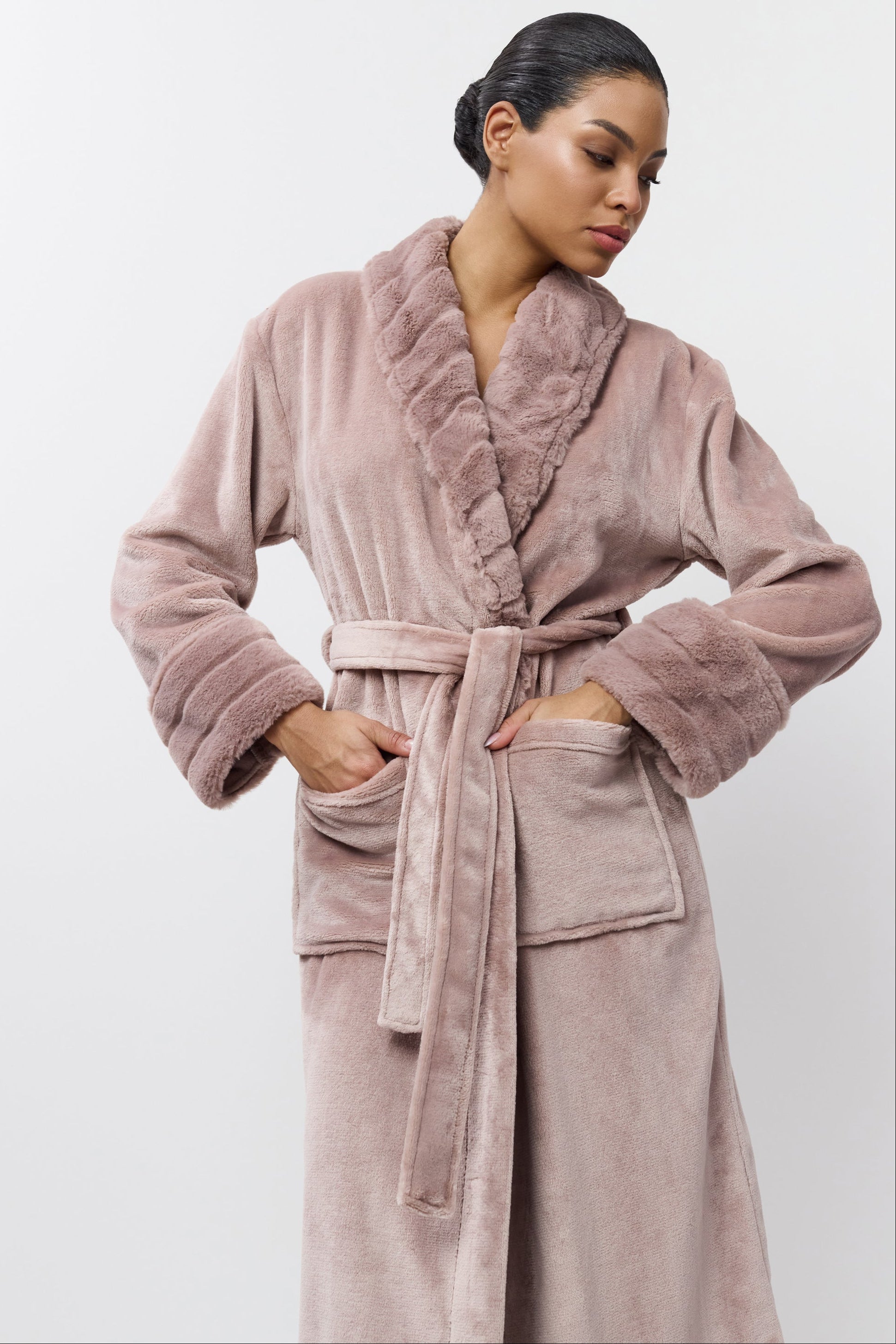 Woman wearing a plush pink robe against a white background