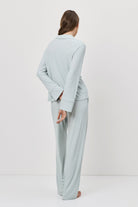 Woman wearing a light blue outfit standing against a white background