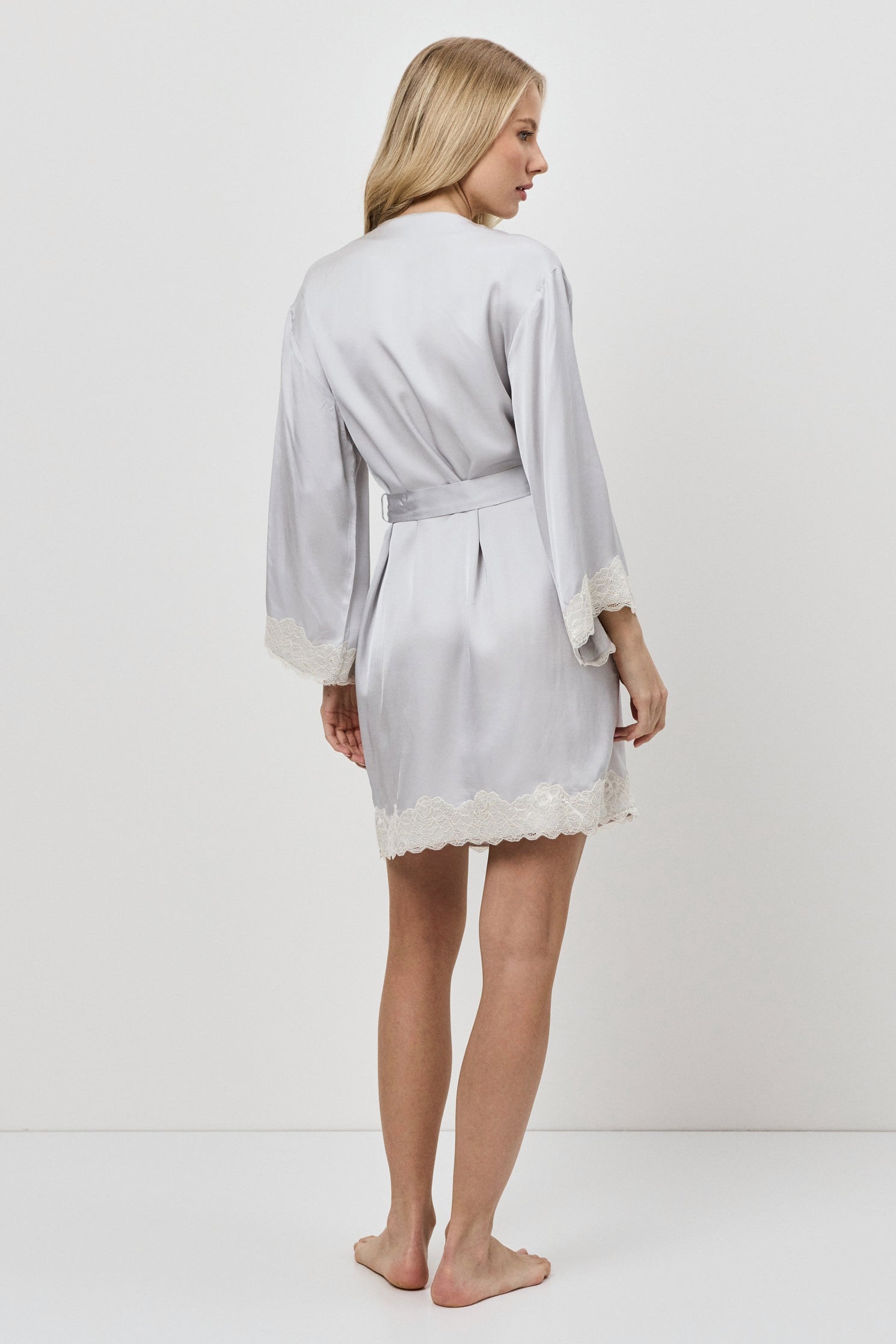 Woman wearing a light gray robe with lace trim on a white background