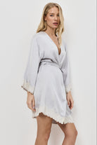 Woman wearing a light gray robe with lace trim on a white background