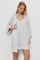 Woman wearing a light gray gown over a gray nightdress on a plain background