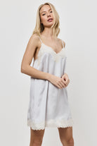 Woman wearing a light gray nightdress with lace trim on a white background