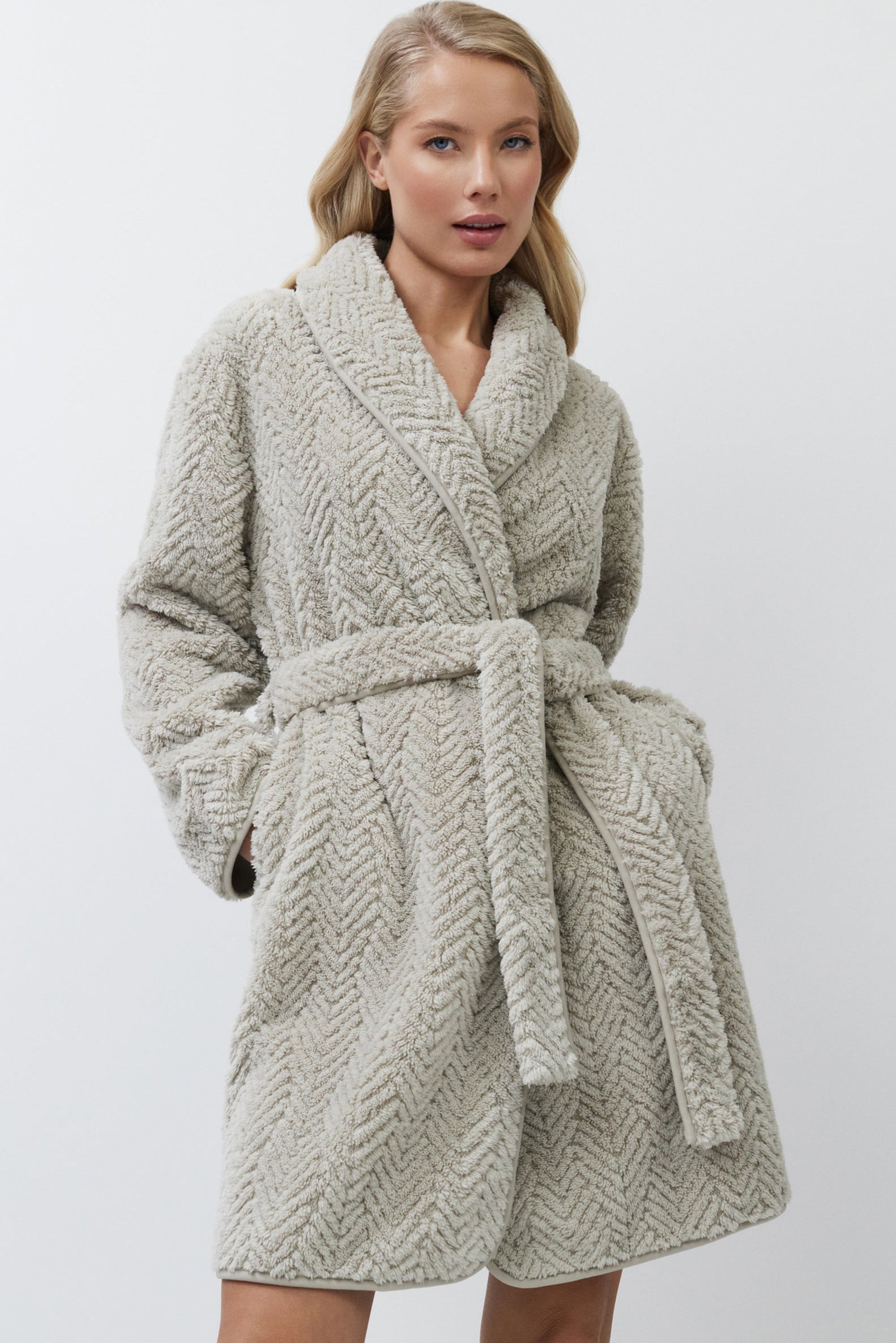 Woman wearing a textured beige bathrobe against a plain background
