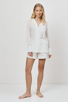 Woman wearing a white resort wear set on a plain background