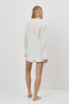 Person wearing a white long-sleeve resort weatr shirt and shorts on a white background