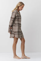 Woman wearing a plaid nightdress against a white background