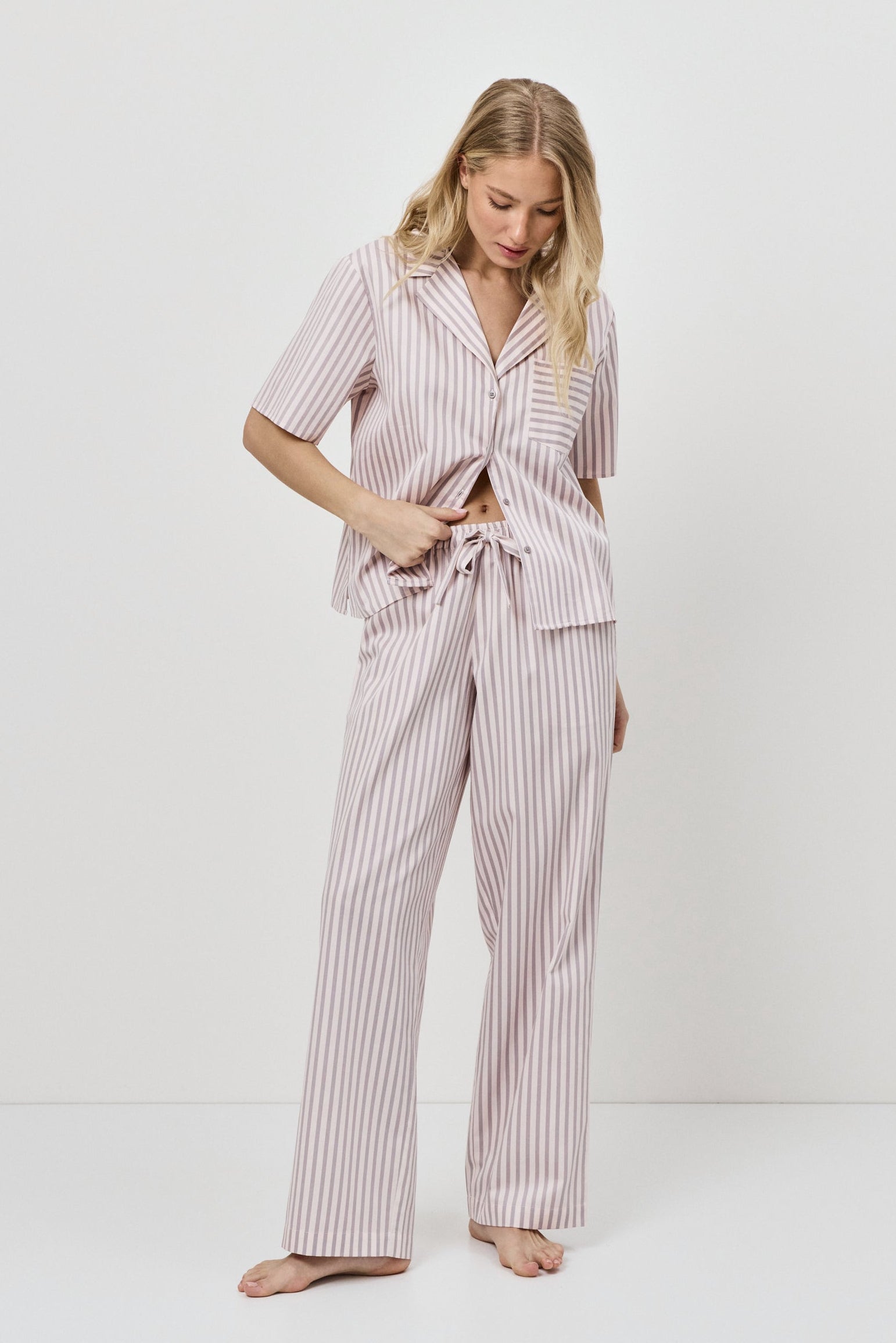 Woman wearing a pink striped pajama set on a white background