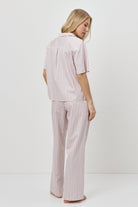Woman wearing a pink striped pajama set on a white background