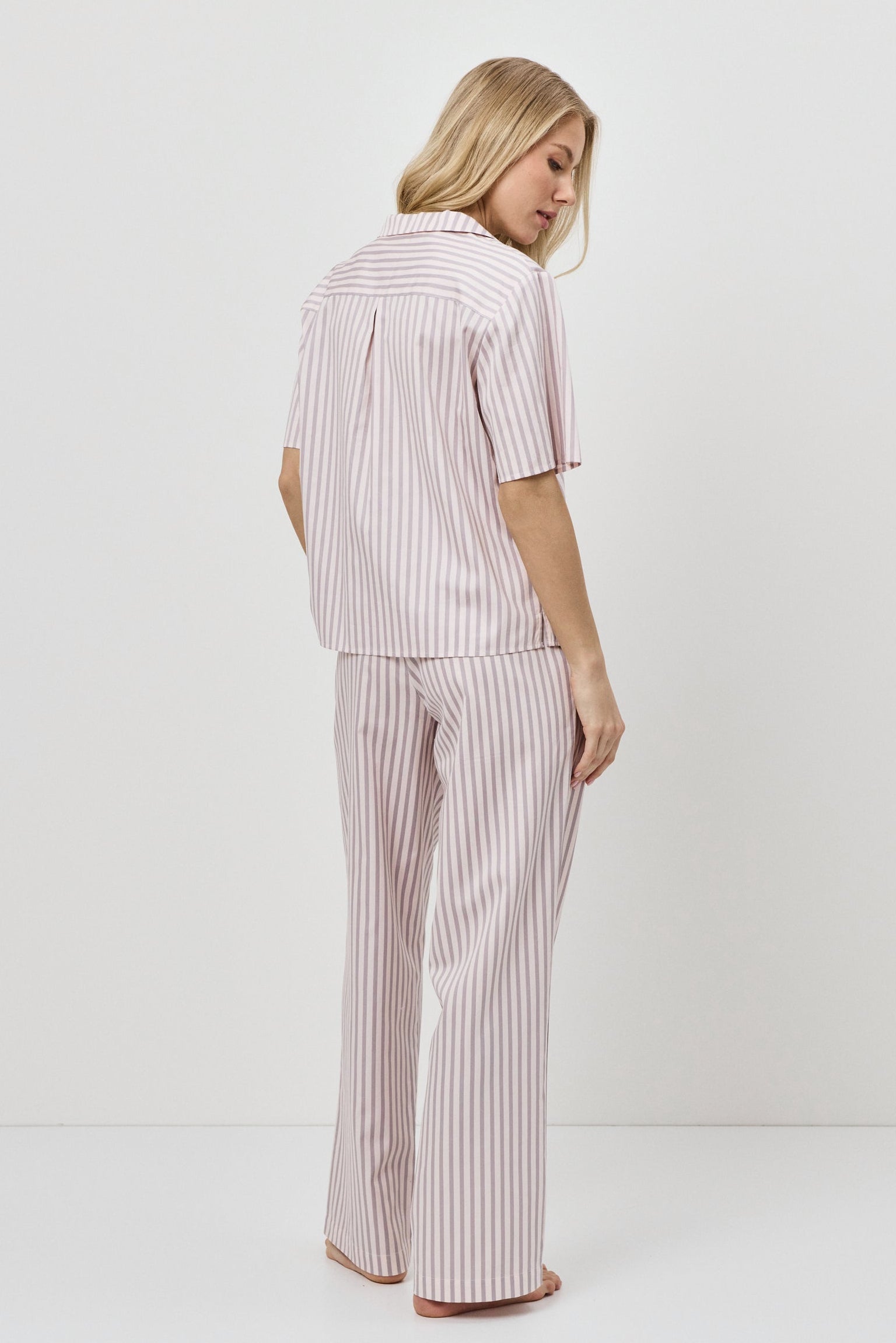 Woman wearing a pink striped pajama set on a white background