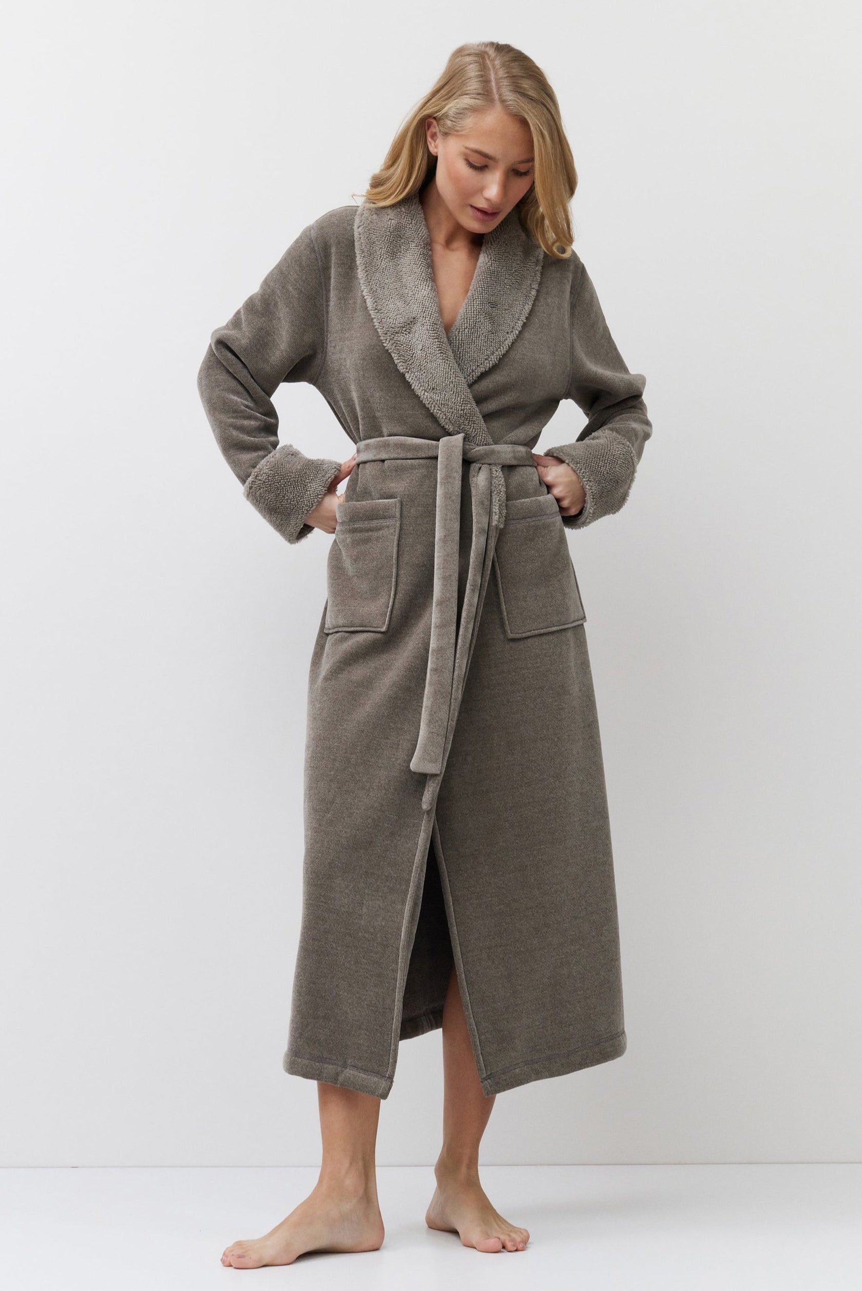 Woman wearing a long brown bathrobe against a white background