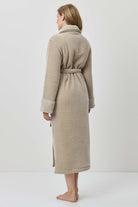 Woman wearing a beige robe against a white background