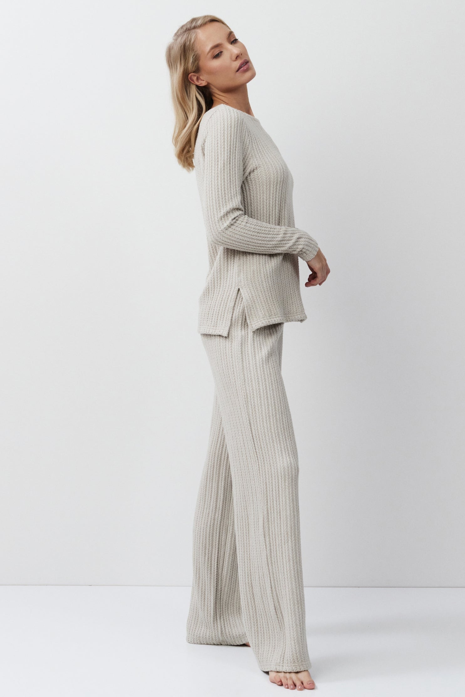 Woman wearing a beige suit standing against a white background