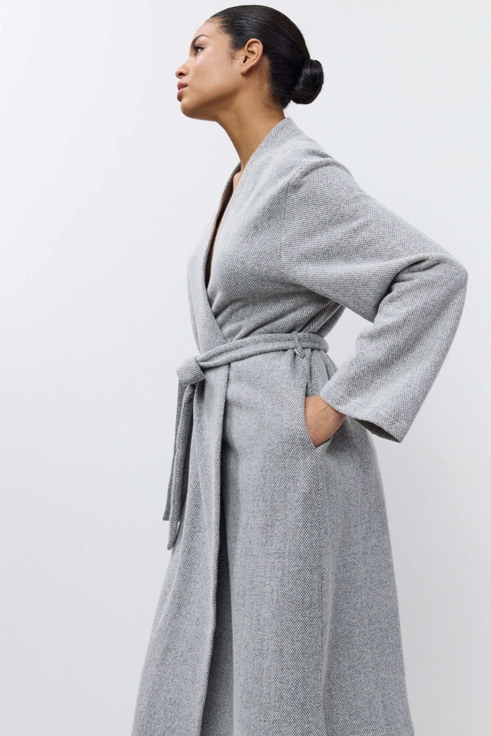 Woman wearing a gray bathrobe against a white background