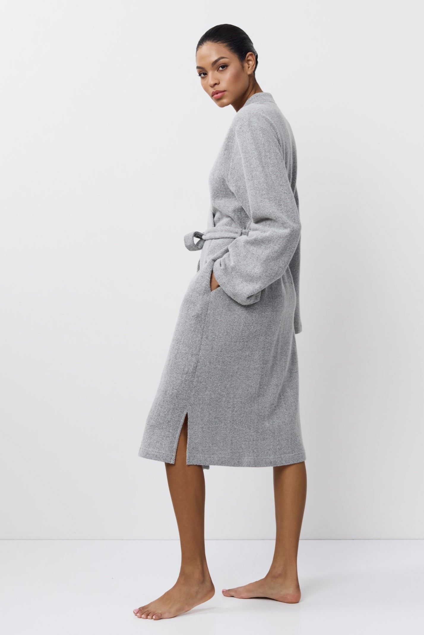 Person wearing a gray 
bathrobe on a white background