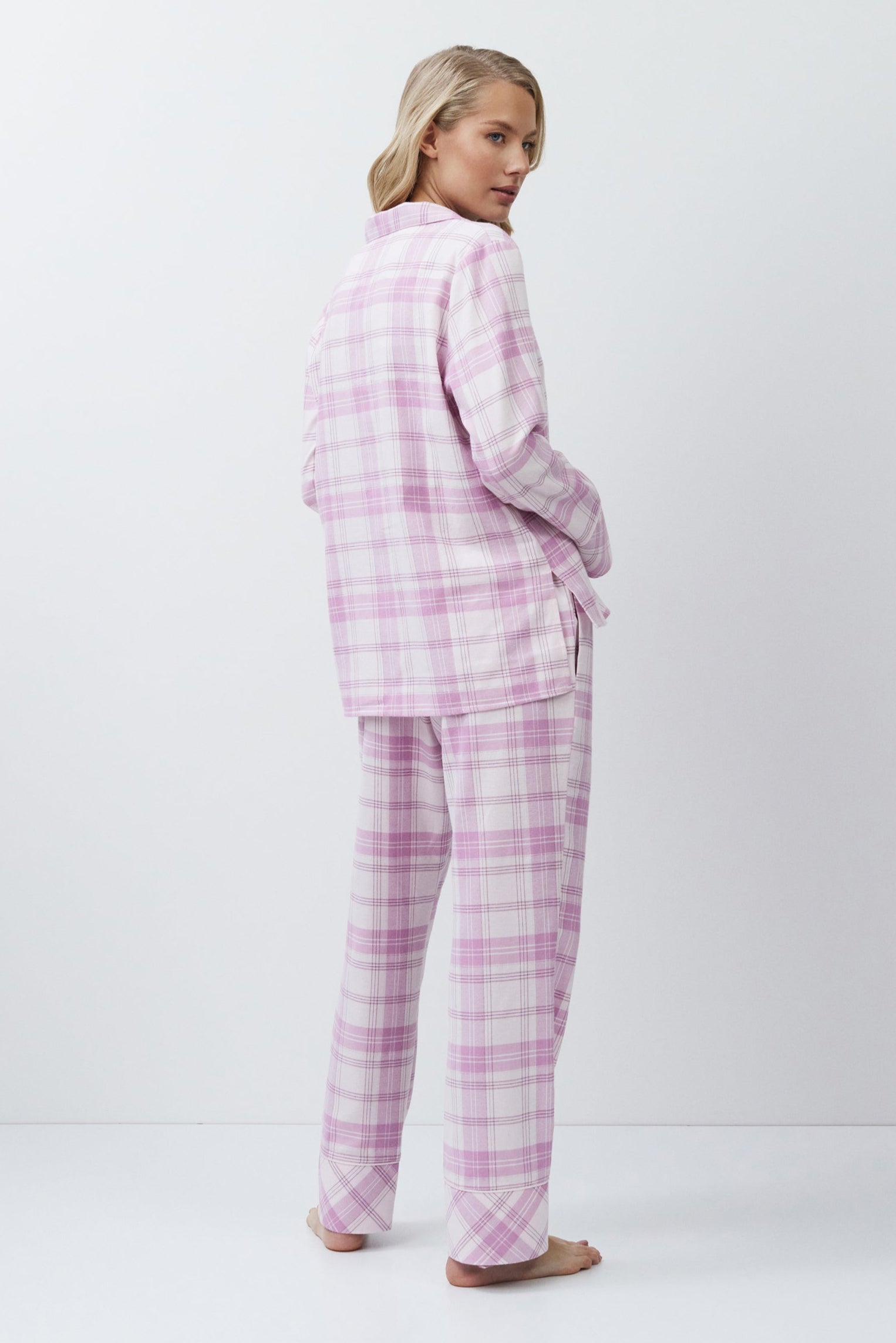 Person wearing a pink plaid pajama set on a white background