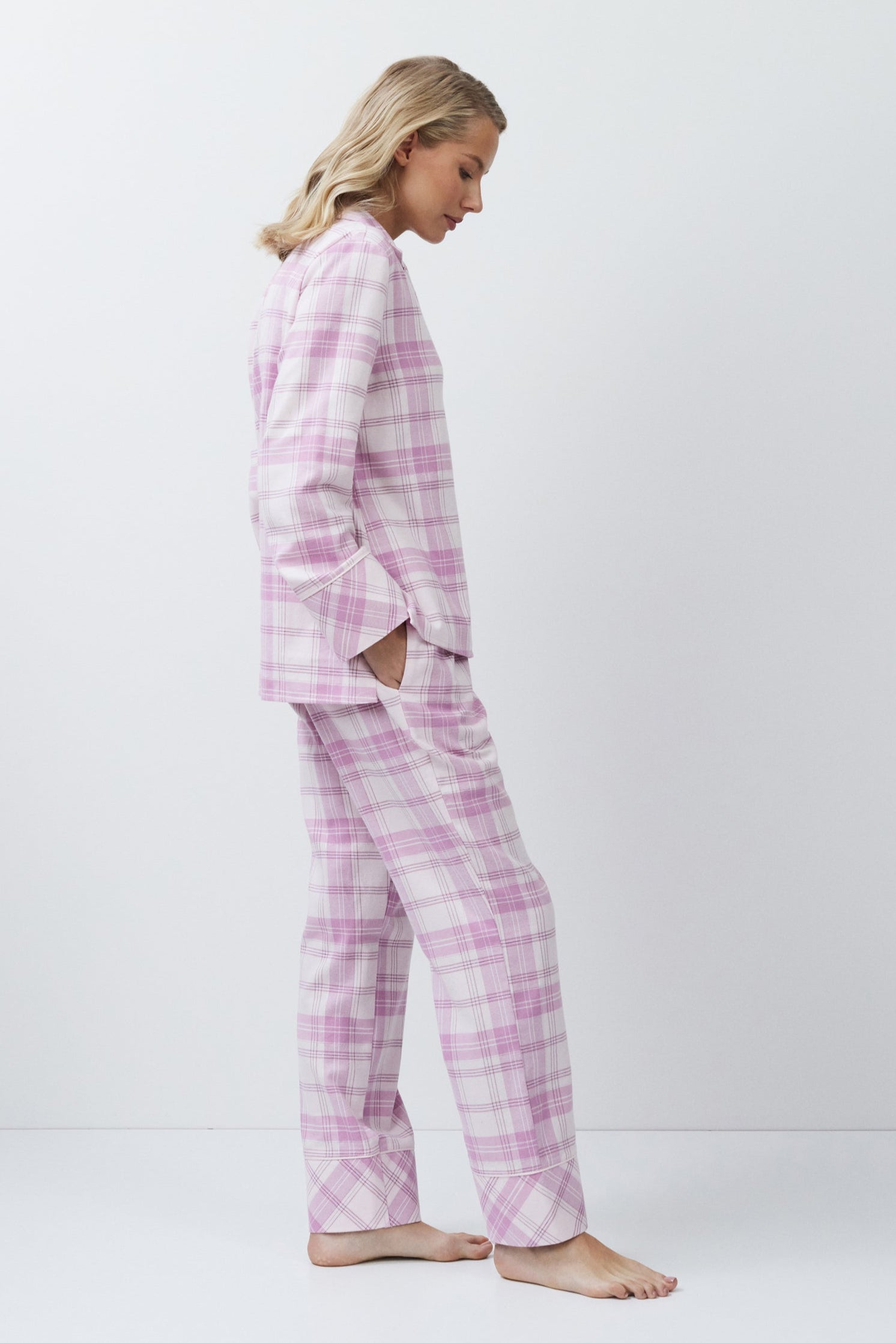 Woman wearing pink plaid pajamas against a white background