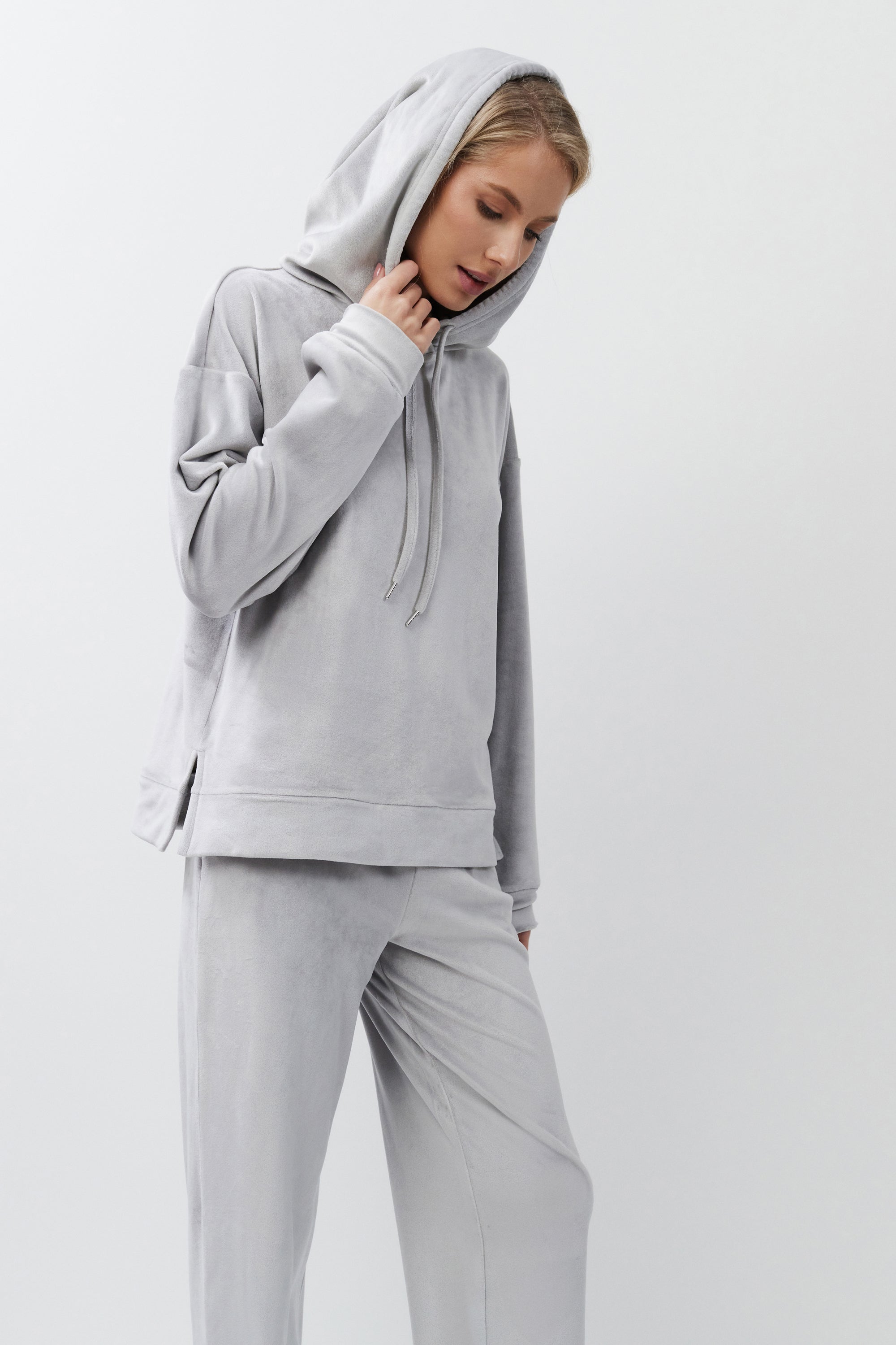Person wearing a gray hoodie and pants on a white background