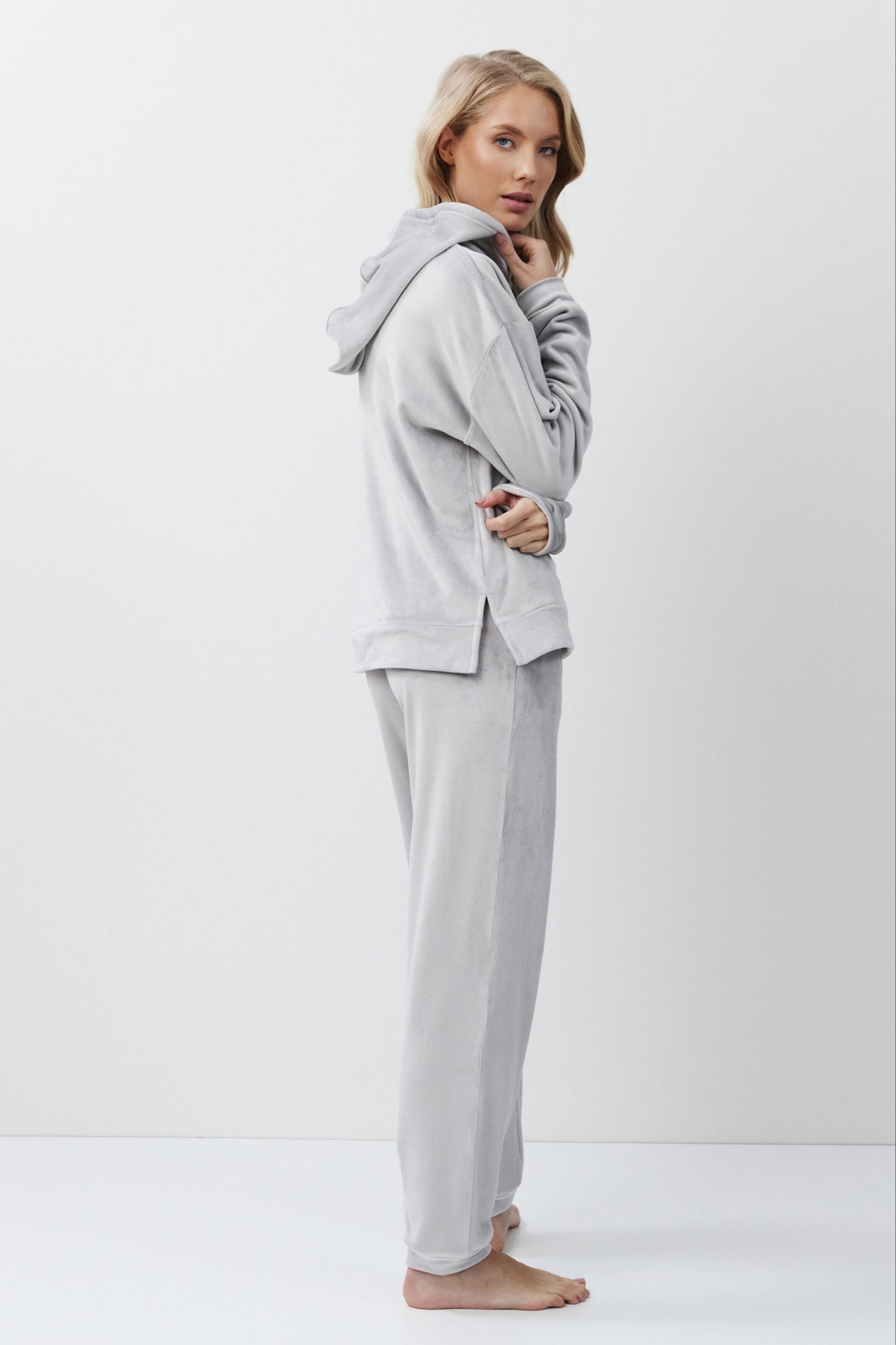 Woman wearing a gray hoodie and pants on a white background