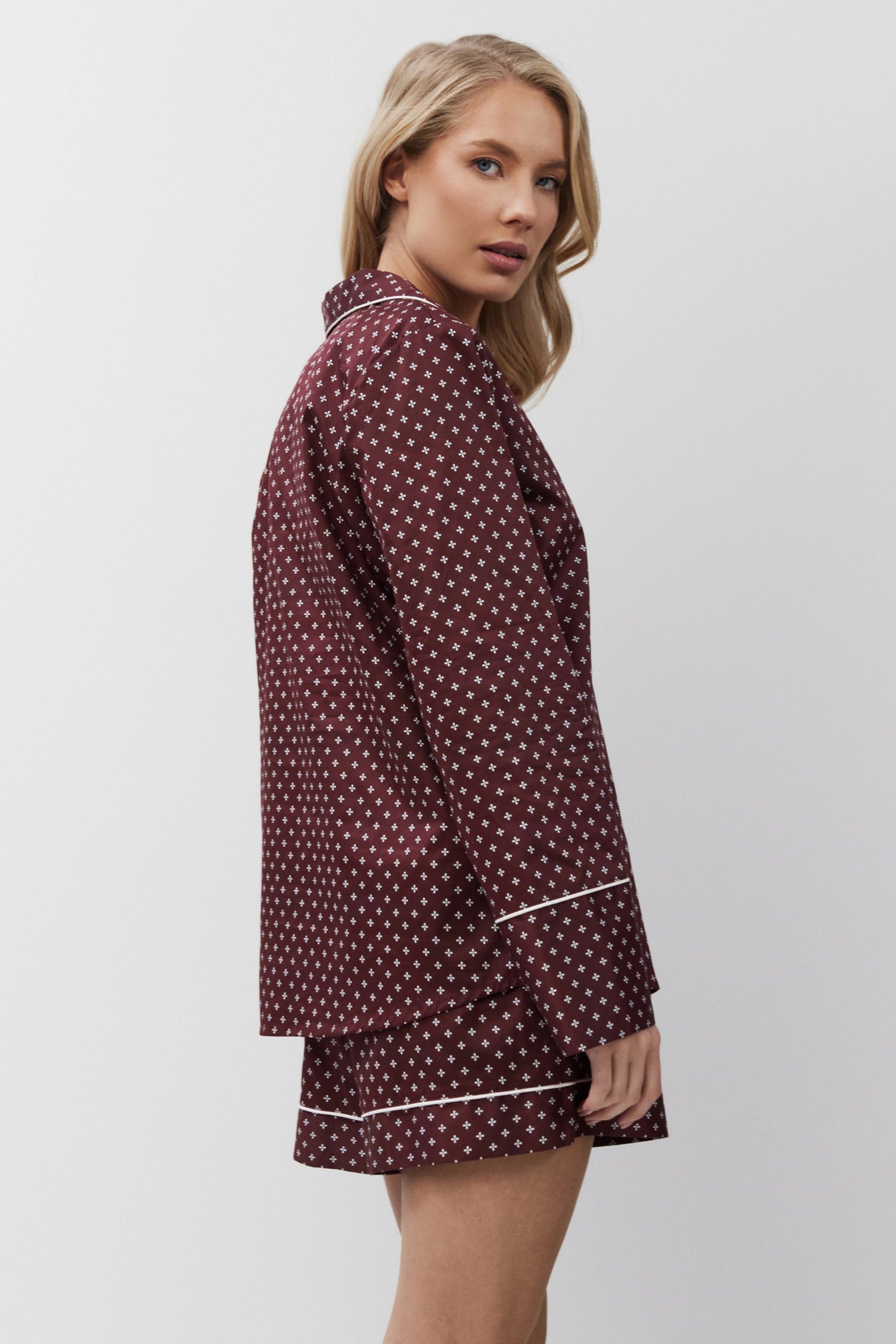 Woman wearing a burgundy pajama set on a white background