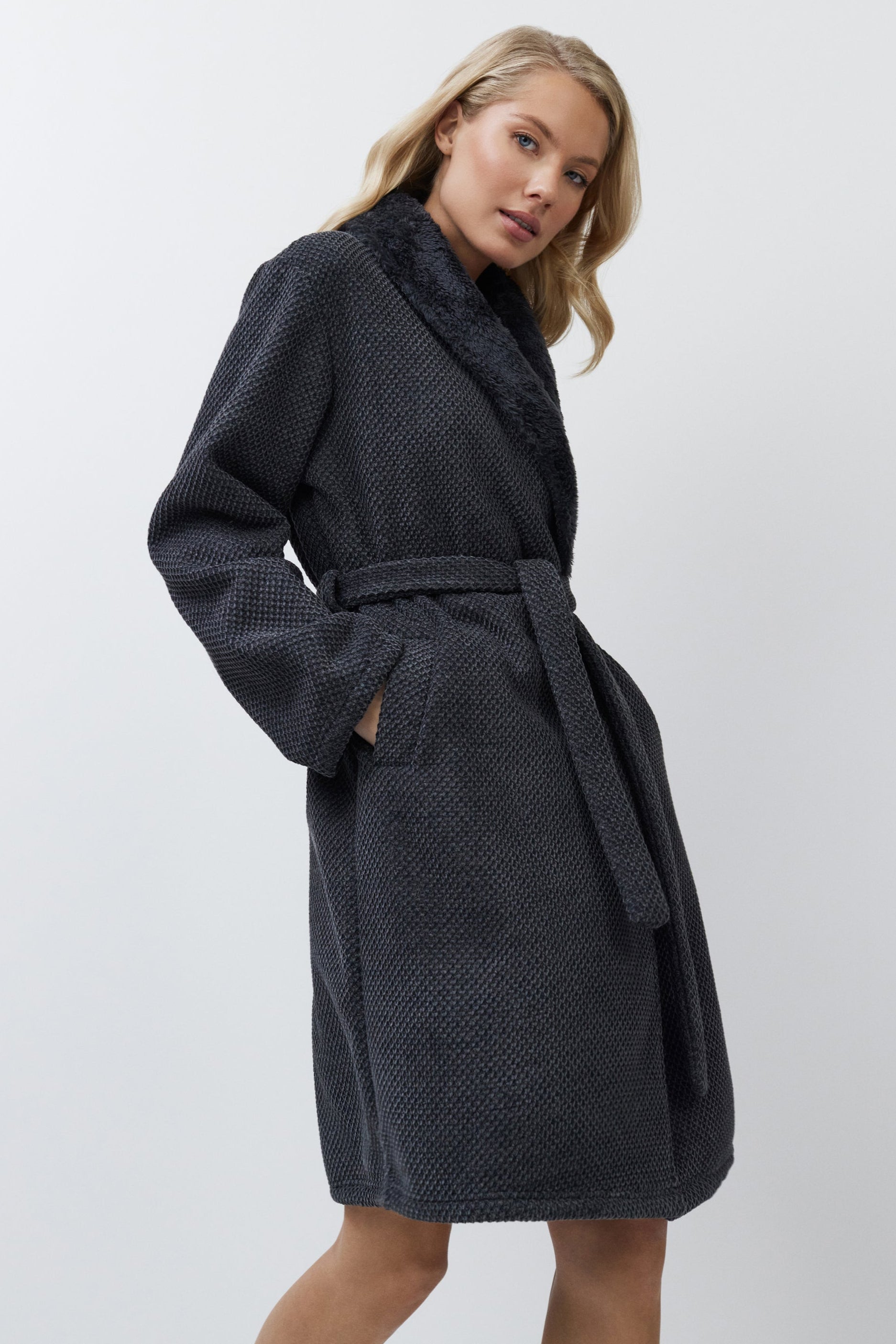 Woman wearing a dark gray textured bathrobe on a white background
