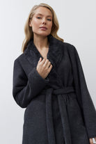 Woman wearing a dark gray textured bathrobe against a white background