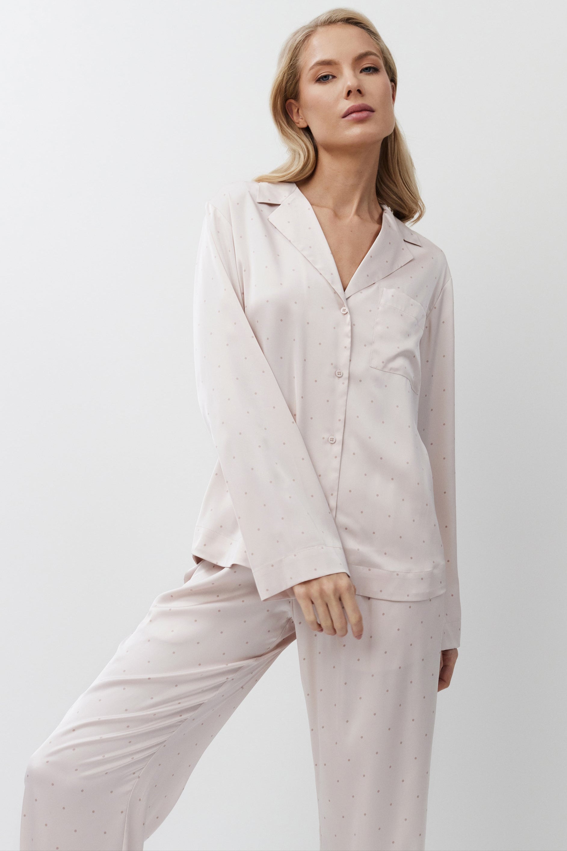 Woman wearing a light pink pajama set against a white background