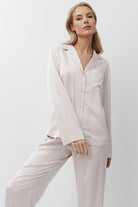 Woman wearing a light pink pajama set against a white background