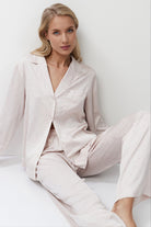 Woman wearing a light pink pajama set sitting.