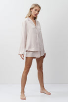 Woman wearing a light pink pajama set on a white background