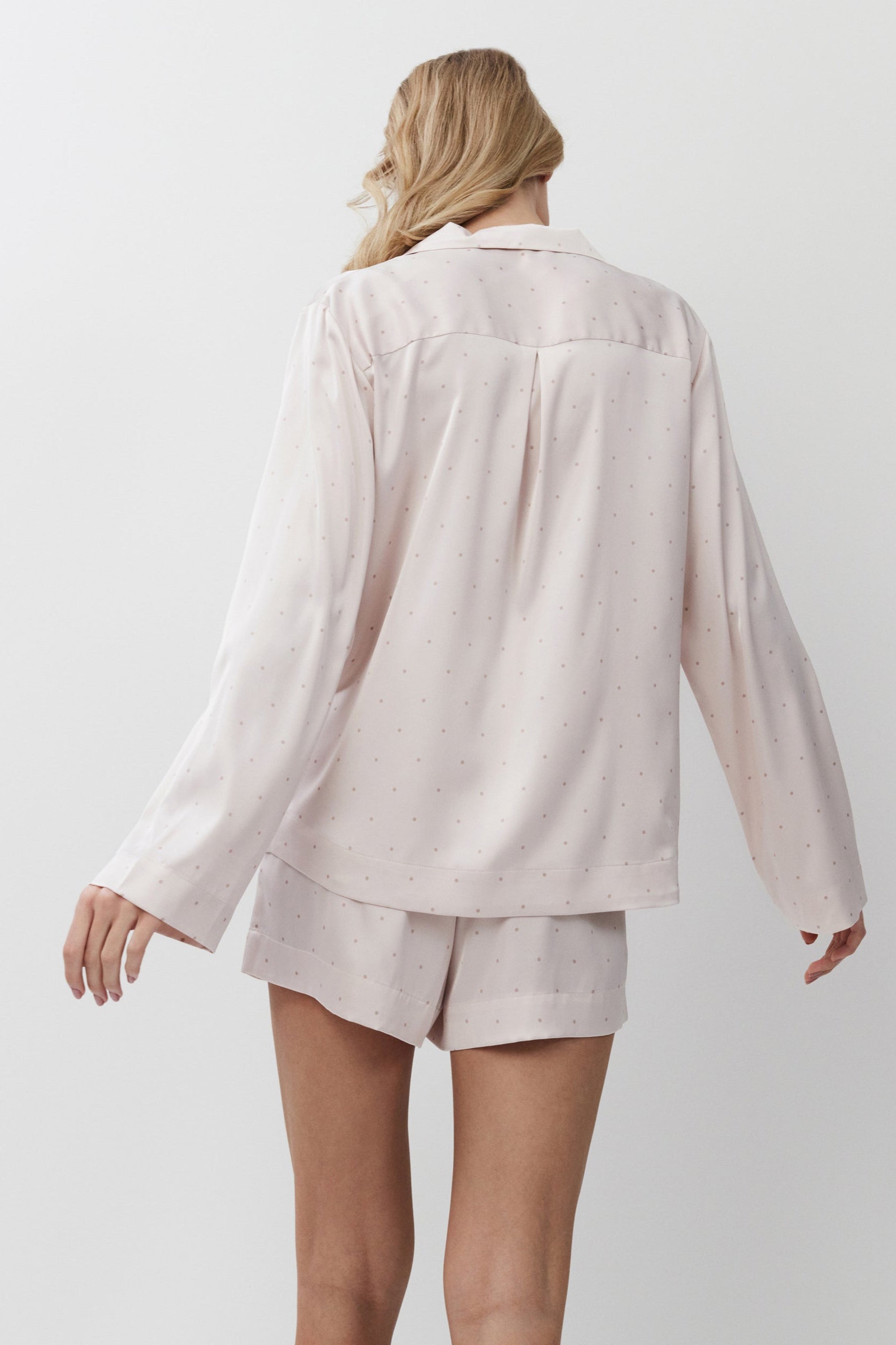 Person wearing a light pink pajama set on a white background