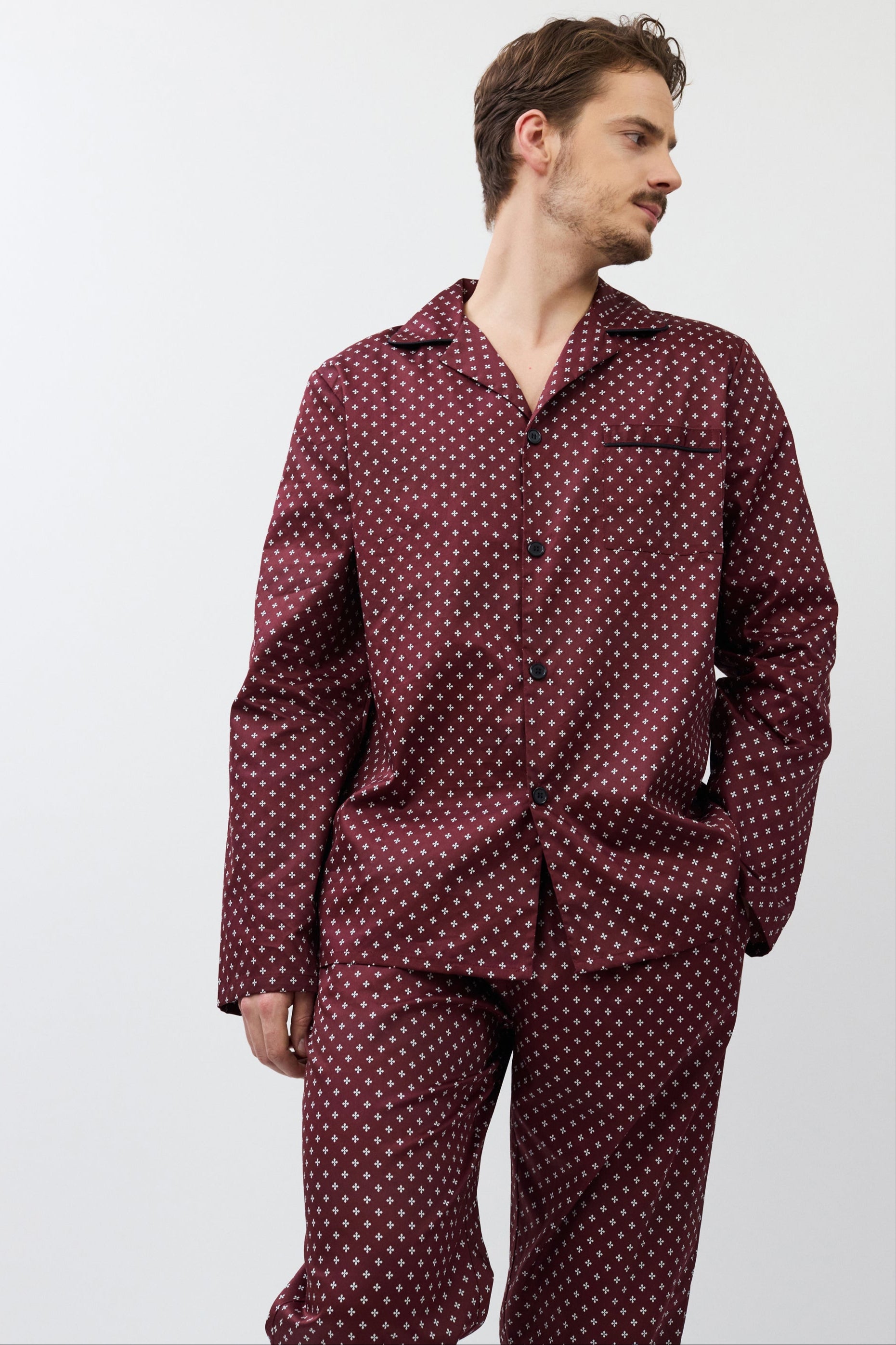 Man wearing a burgundy patterned pajama set against a white background