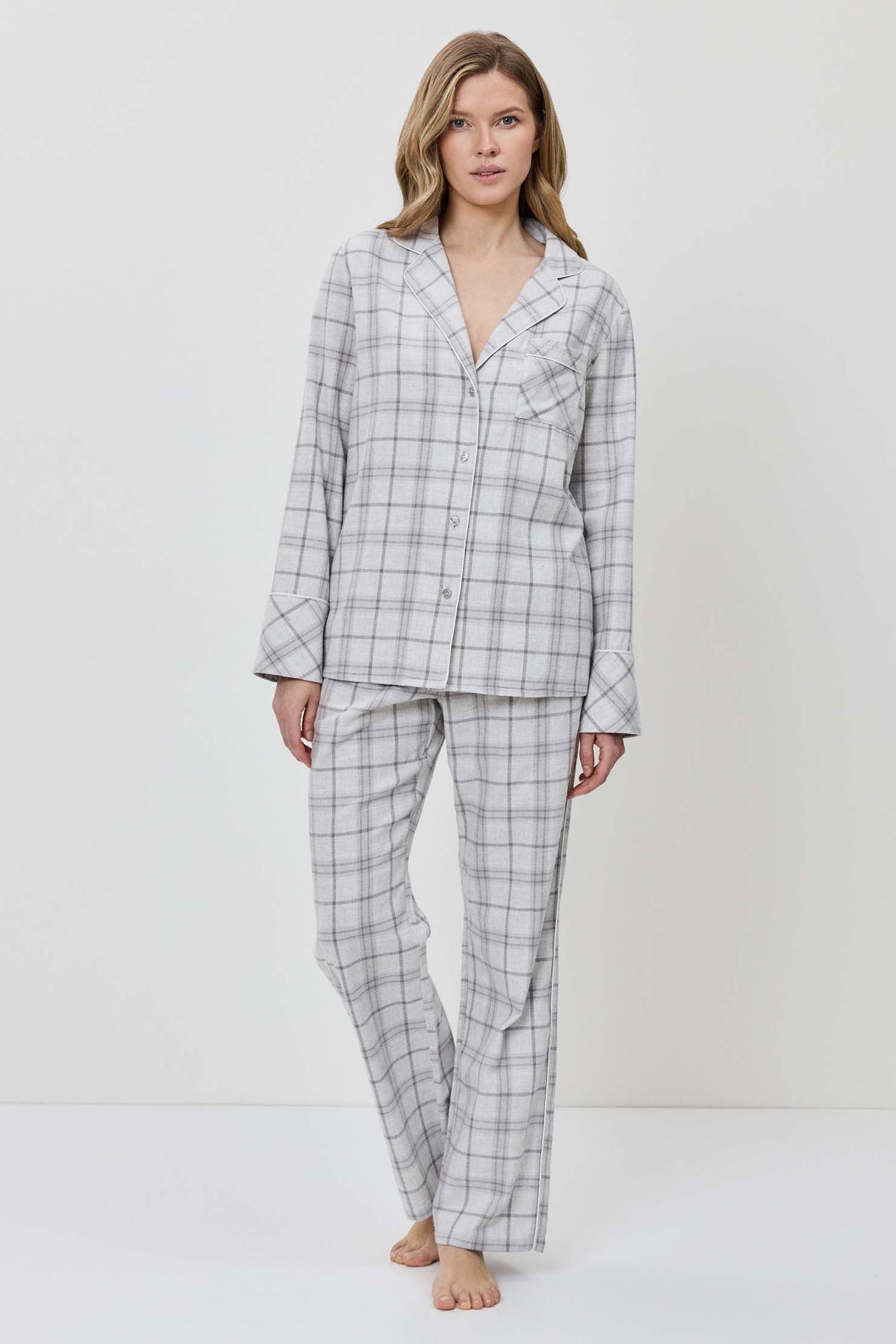 Woman wearing a gray checkered pajama set against a white background