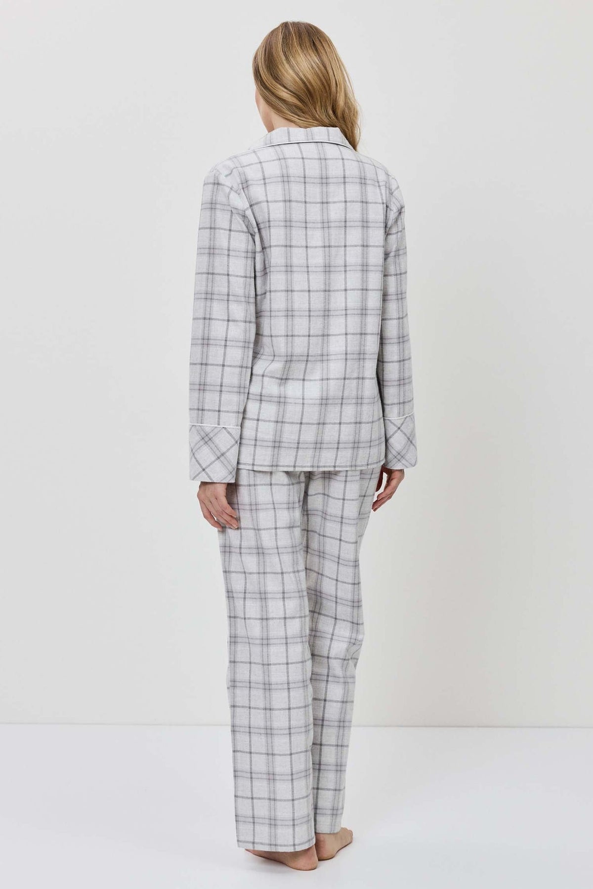 Person wearing a gray checkered suit standing against a white background