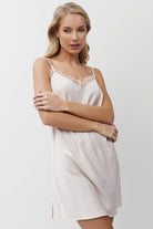 Woman wearing a pink nightdress against a plain background