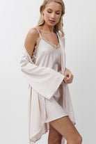 Woman wearing a pink lace nightdress with a matching gown on a plain background