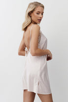 Woman wearing a pink nightdress with lace details on a plain background