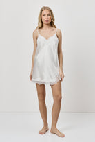 Woman wearing a white nightdress against a plain background