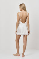 Woman wearing a white lace nightdress against a plain background