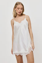 Woman wearing a white nightdress against a plain background