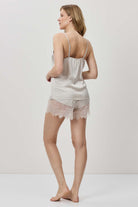Woman wearing a light-colored lace camisole and shorts on a white background