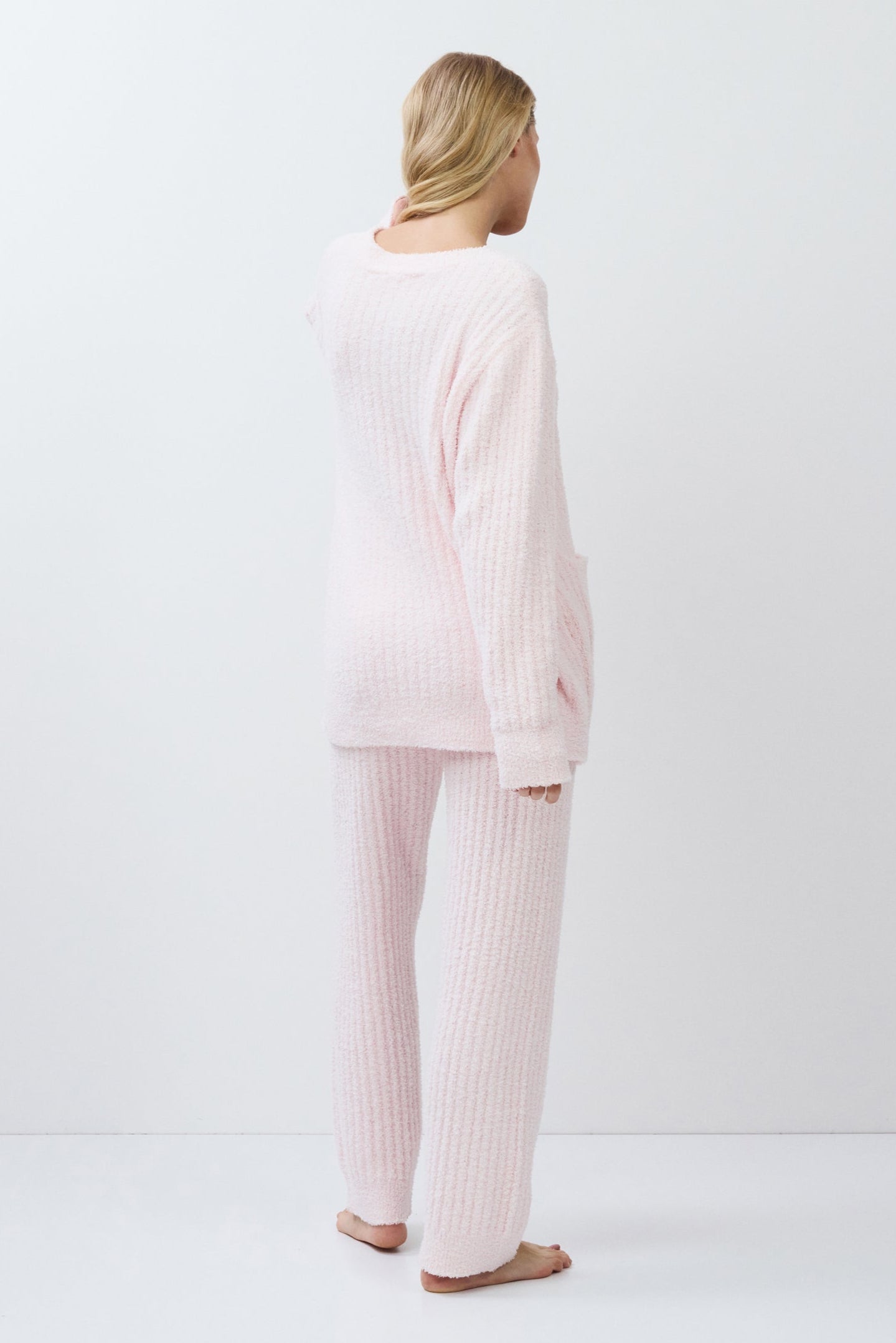 Person wearing a light pink set standing against a white background