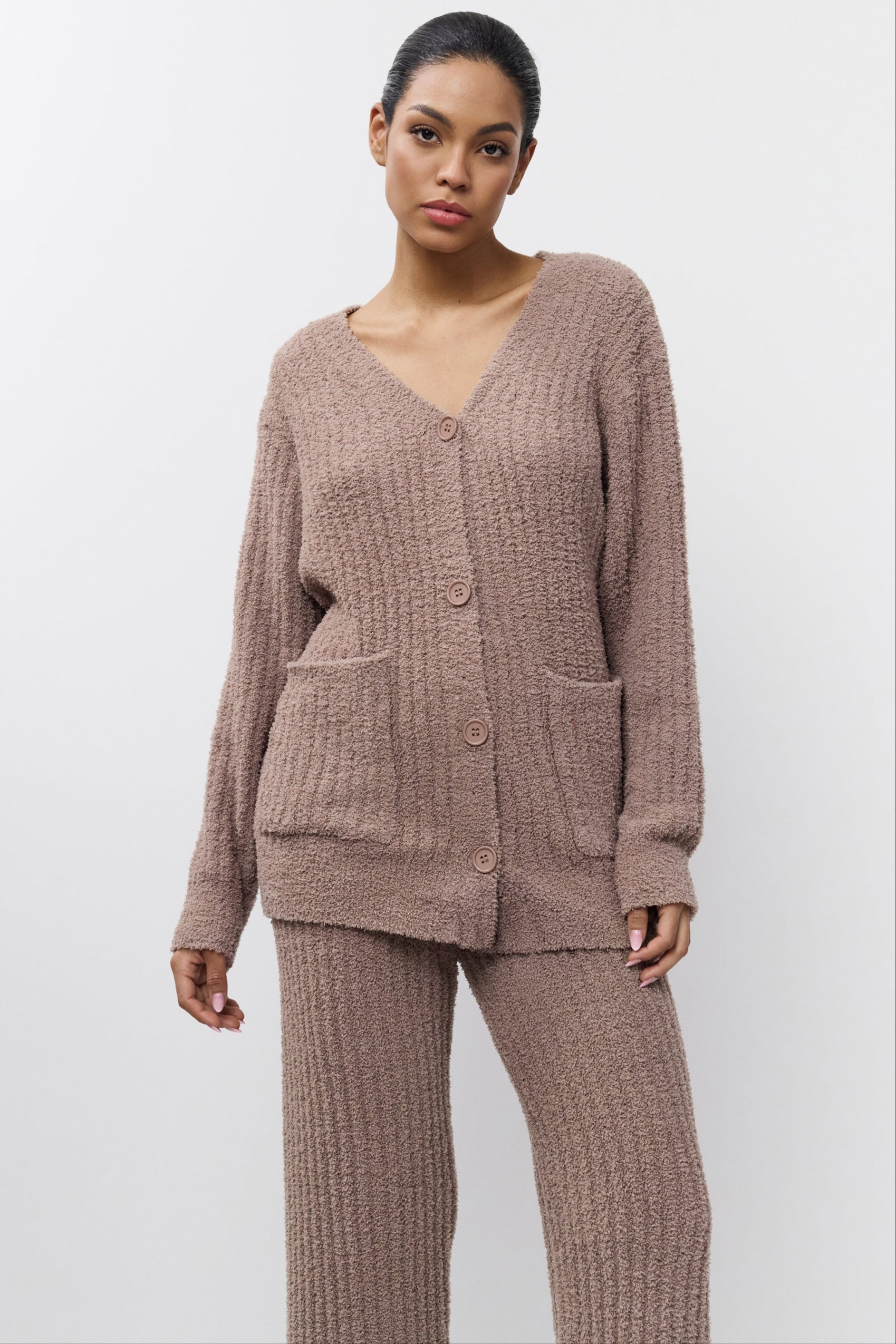 Woman wearing a brown knitted cardigan and pants on a white background
