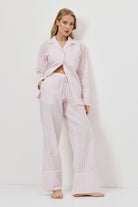 Woman wearing a pink checkered pajama set against a white background