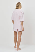 Woman wearing a pink checkered pajama set on a white background