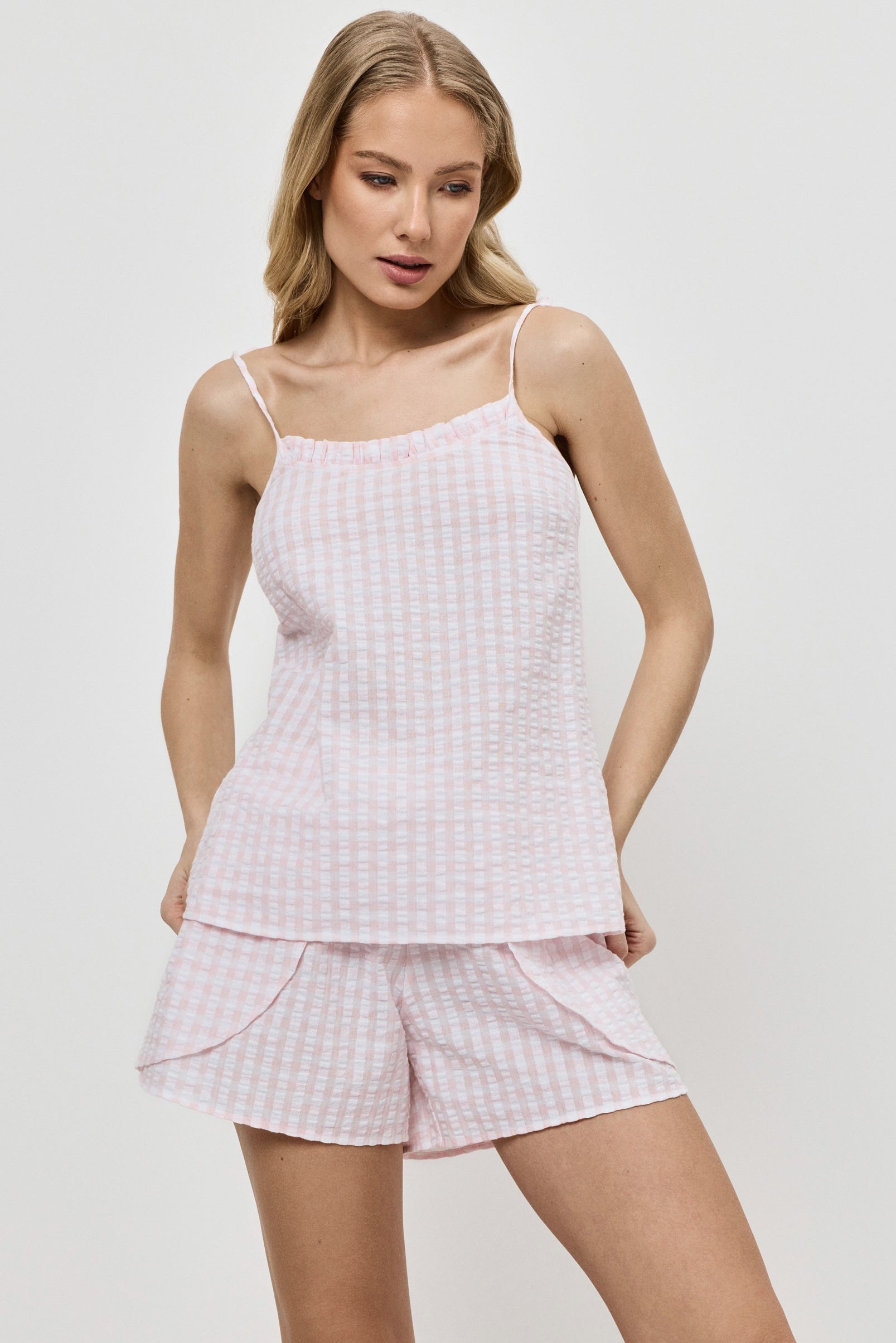 Woman wearing a pink checkered pajama set against a white background