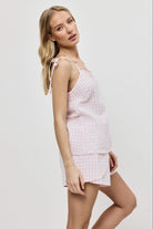 Woman wearing a pink checkered pajama set on a white background